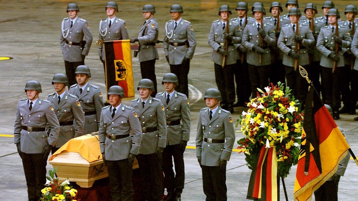 Soldaten mit Deutschland-Flaggen an einem Sarg | Bildquelle: Dpa Soldaten mit Deutschland-Flaggen an einem Sarg