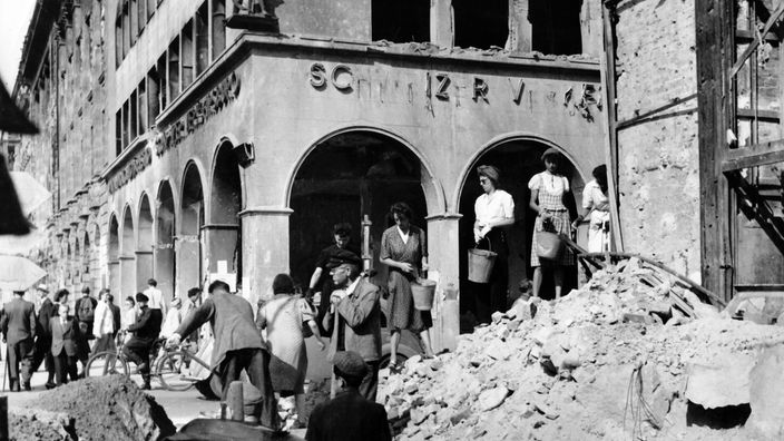 Frauen und Männer beim Aufräumen der Trümmer eines Berliner Hauses.