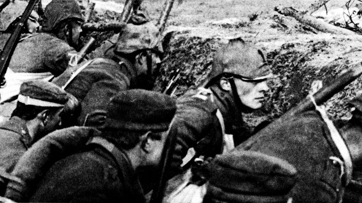 Schwarz-weiß Bild von 1916: Soldaten verharren bewaffnet im Schützengraben und warten auf Befehl. 