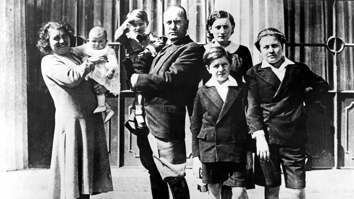 Das Foto zeigt Mussolini in Zivil inmitten seiner Familie. Seine Ehefrau Rachele hält das jüngste Baby auf dem Arm.
