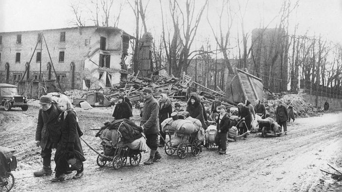 Eine Gruppe von Flüchtlingen in einer zerstörten Ortschaft in Ostpreußen