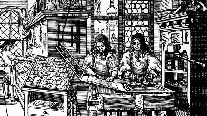 Zwei Buchdrucker bei der Arbeit an einer Gutenberg-Presse