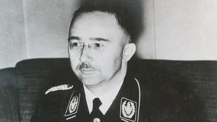 Schwarzweiß-Porträtfoto von Heinrich Himmler mit Nickelbrille, schmalem Schnurrbart und SS-Uniform.