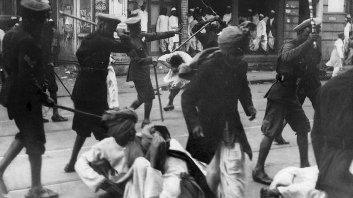 In Bombay gehen Polizisten mit Bambusstöcken auf indische Demonstranten los