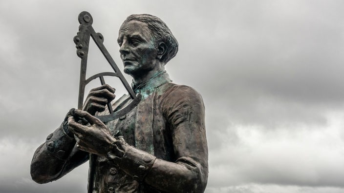 Eine Bronze-Statue von James Cook zeigt ihn mit einem astronomischen Messgerät in den Händen