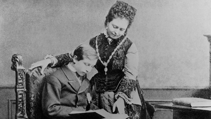 Der sitzende Prinz Wilhelm und seine Mutter lesen ein Buch