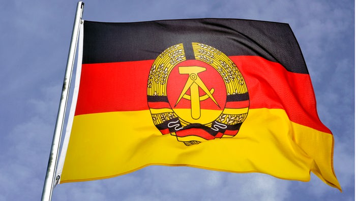 Eine Flagge der ehemaligen DDR von unten gegen den Himmel fotografiert