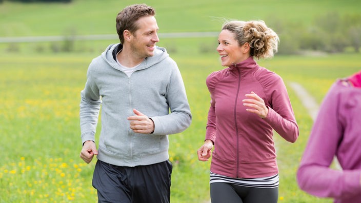 Frau und Mann joggen über einen Feldweg
