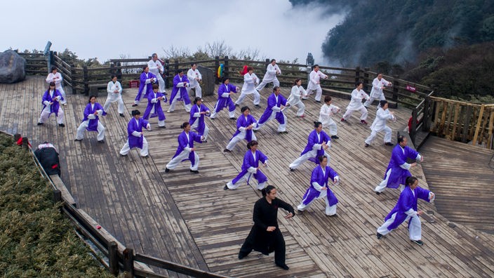 Eine Gruppe von Menschen in traditioneller Kleidung auf einem Berg beim Taiji 