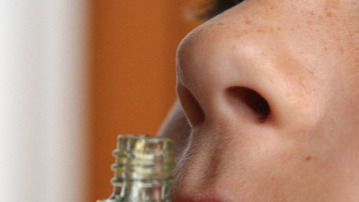 Eine Nase riecht an einer Parfümflasche