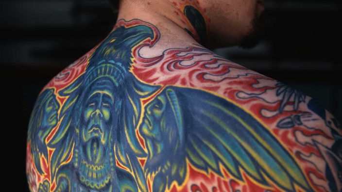 Ein Mann mit einem Tattoo, das den halben Rücken bedeckt.