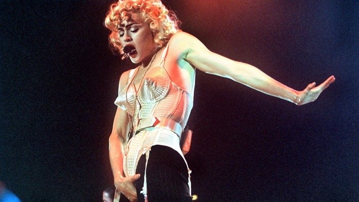 Pop-Sängerin Madonna im Mieder auf der Bühne (1990) | Bildquelle: dpa/Franz-Peter Tschauner Pop-Sängerin Madonna im Mieder auf der Bühne (1990)