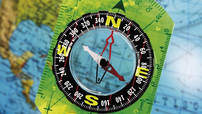 Kompass wird über einen Globus gehalten