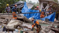 Ersthelfer mit Hund suchen in einem zerstörten Haus in Mexiko nach Überlebenden