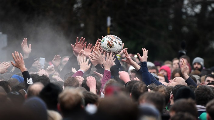 Menschenmenge, die um einen großen Ball rangelt