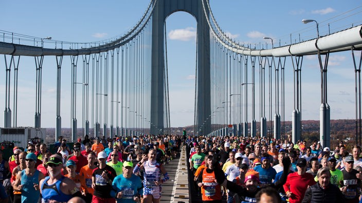 Hunderte Menschen joggen über eine Brücke in New York.