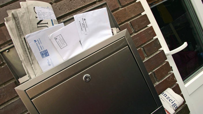 Zeitungen und Briefe stecken in einem Briefkasten