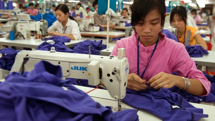 Eine Näherin sitzt in einer vietnamesischen Textilfabrik an einer Nähmaschine