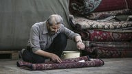 Ein Mann arbeitet an einem Teppich auf einem Teppichbasar in Teheran
