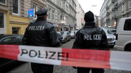 Zwei Polizisten stehen hinter einer Polizeiabsperrung. Im Hintergrund stehen Einsatzfahrzeuge und weitere Polizisten. | Bildquelle: dapd Zwei Polizisten stehen hinter einer Polizeiabsperrung. Im Hintergrund stehen Einsatzfahrzeuge und weitere Polizisten.