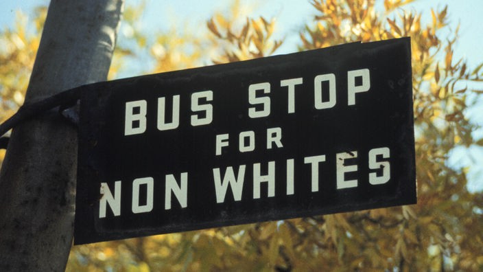 Eine Bushaltestelle in Südafrika zu Zeiten des Apartheid-Regimes. Auf dem Schild steht "Bus Stop for Non-Whites"