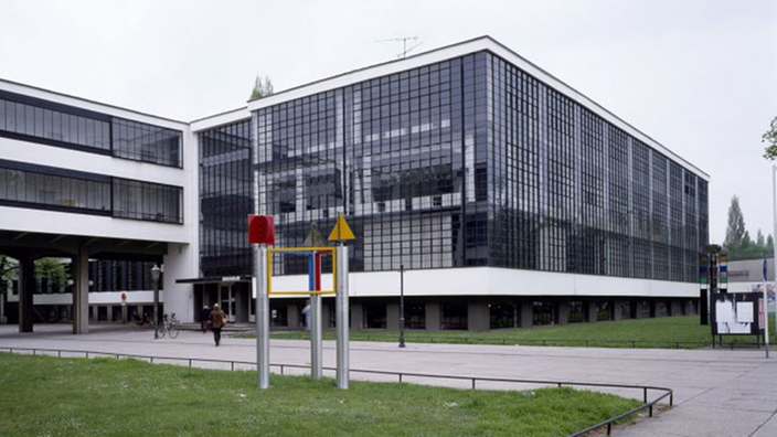 Blick auf den Eingangsbereich des rechteckigen, vollständig verglasten Bauhaus-Gebäudes in Dessau.