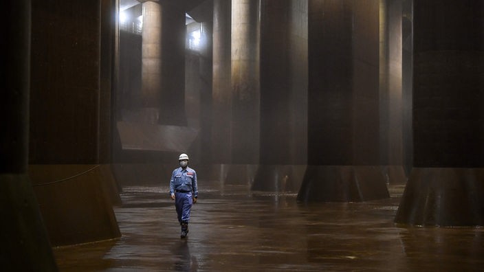 Ein Mann läuft zwischen meterhohen Säulen in einer unterirdischen Halle