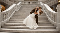 Ein Brautpaar umarmt sich romantisch auf einer Treppe.