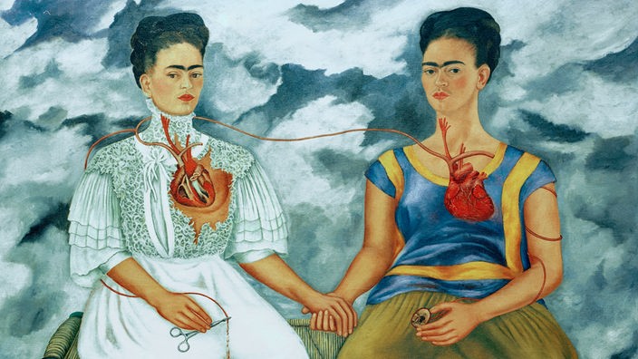 Im Bild „Die zwei Fridas“ (1939) ist Frida Kahlo doppelt zu sehen: einmal in einem traditionell europäischen Kleid, einmal in einem traditionell mexikanischen