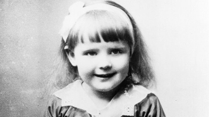 Schwarzweiß-Foto eines kleinen Mädchens im Kleid.