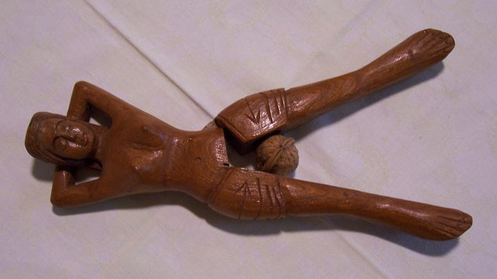 Holznussknacker in Form einer nackten Frau. Zwischen ihren Schenkel werden die Nüsse geknackt.
