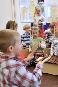 Zwei blonde Schülerinnen der zweiten Klasse spielen im Musikunterricht auf der Blockflöte.