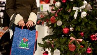 Eine Frau schlendert neben einem Weihnachtsbaum mit einer Einkaufstüte spazieren.