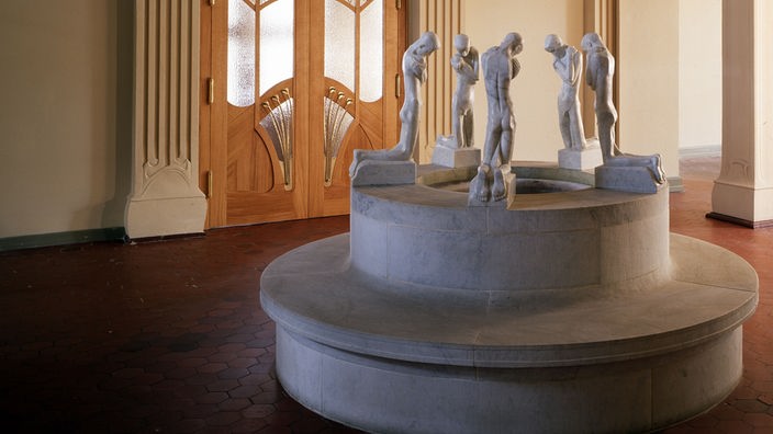 Eingangshalle des Osthaus Museums in Hagen mit einem weißen Brunnen mit mehreren Figuren.