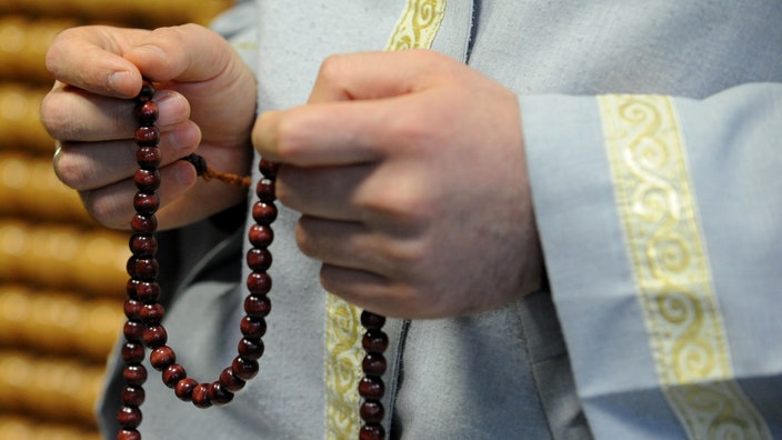 Ein Imam, Vorbeter beim islamischen Gebet, hält am in einer Moschee in Hamburg seine Gebetskette. | Bildquelle: dpa Ein Imam, Vorbeter beim islamischen Gebet, hält am in einer Moschee in Hamburg seine Gebetskette.