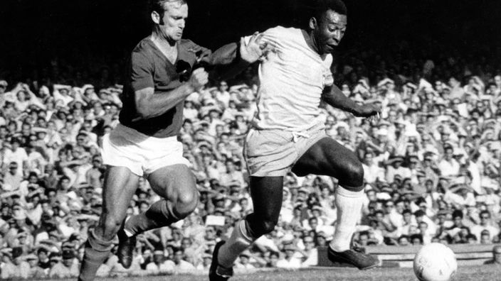 Schwarzweiß-Bild: Pelé und Gegenspieler während eines Fußballspiels.