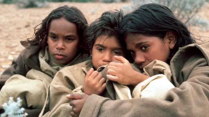 Filmszene "Long Walk Home": Drei Aborigines-Mädchen hüllen sich in Mäntel.