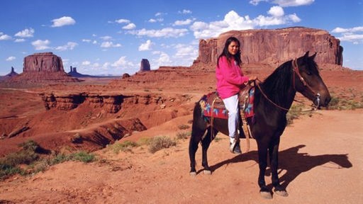 Junge Indianerin auf einem Pferd vor einem Tafelberg im Südwesten der USA.