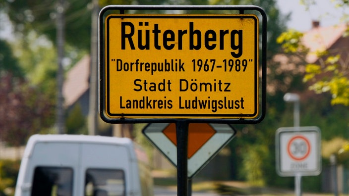 Ortseingangsschild von Rüterberg mit dem Hinweis "Dorfrepublik Rüterberg" | Bildquelle: picture alliance / dpa Ortseingangsschild von Rüterberg mit dem Hinweis "Dorfrepublik Rüterberg"