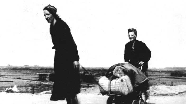 Zwei Frauen ziehen im April 1945 einen Handkarren über Land.