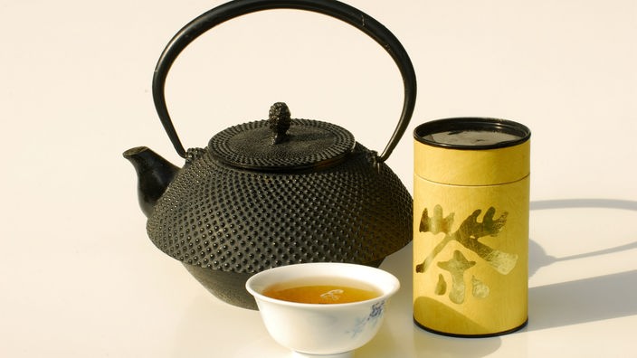 Dose mit grünem Tee, Teekanne und Schale mit grünem Tee
