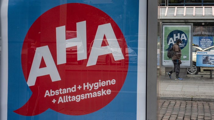 Eine Werbetafel mit der Aufschrift "AHA = Abstand + Hygiene + Alltagsmaske" an einer Bushaltestelle