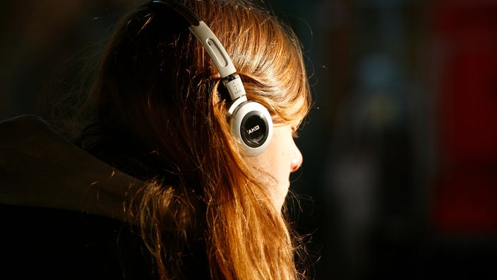 Junge Frau mit Kopfhörer ist mit geschlossenen Augen ganz in die Musik versunken