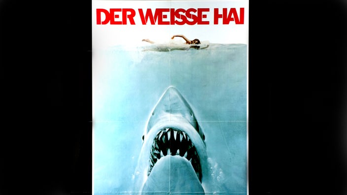 Kinoplakat von "Der Weiße Hai": Ein gemalter Hai nähert sich von unten mit geöffnetem Maul einer Schwimmerin.