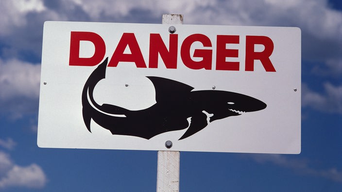 Schild mit der Aufschrift "Danger" und dem Bild eines Hais.