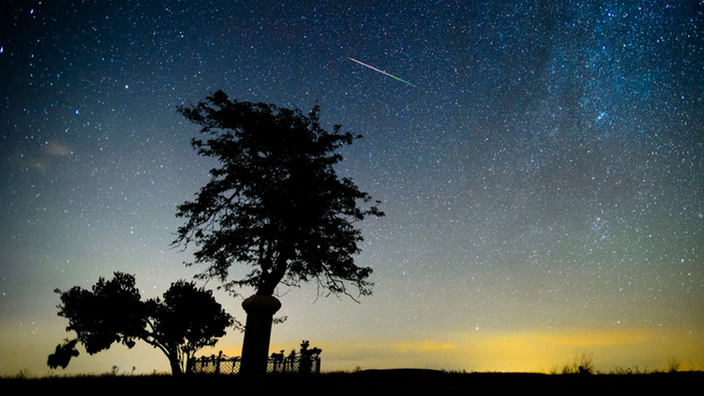 Ein Meteor verglüht am Nachthimmel.
