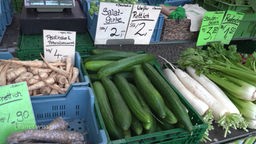Gemüse auf einem Wochenmarkt mit handgeschriebenen Preisschildern.