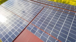 Solarmodule auf einem Dach, im Hintergrund blühendes Rapsfeld | Bildquelle: imago images/Countrypixel Solarmodule auf einem Dach, im Hintergrund blühendes Rapsfeld