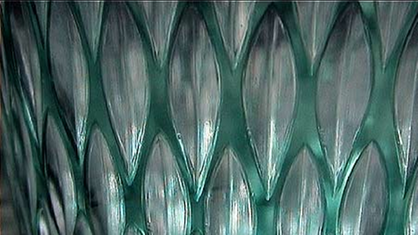 Helles blaugrünes Glas mit länglichem geschnittenen Muster. Das Muster erscheint als Klarglas.
