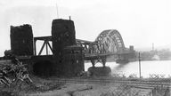  Schwarzweiß-Bild: Stark beschädigte Eisenbahnbrücke.